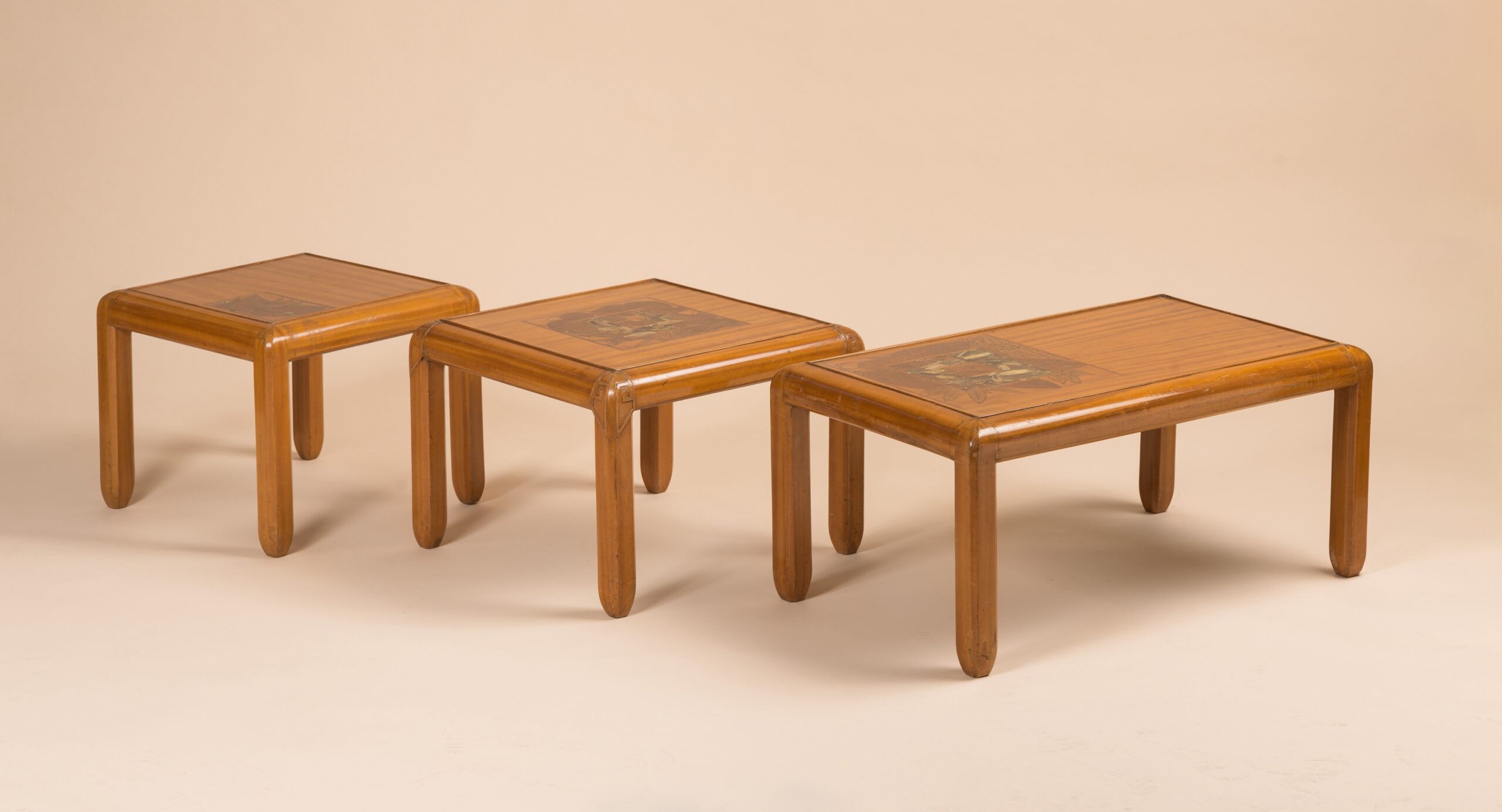 Three tables in East Indies Satinwood by Georges De Feure, c.1910. Table tops marquetry with a floral inlay, mother of pearls, ebony and fruit wood.