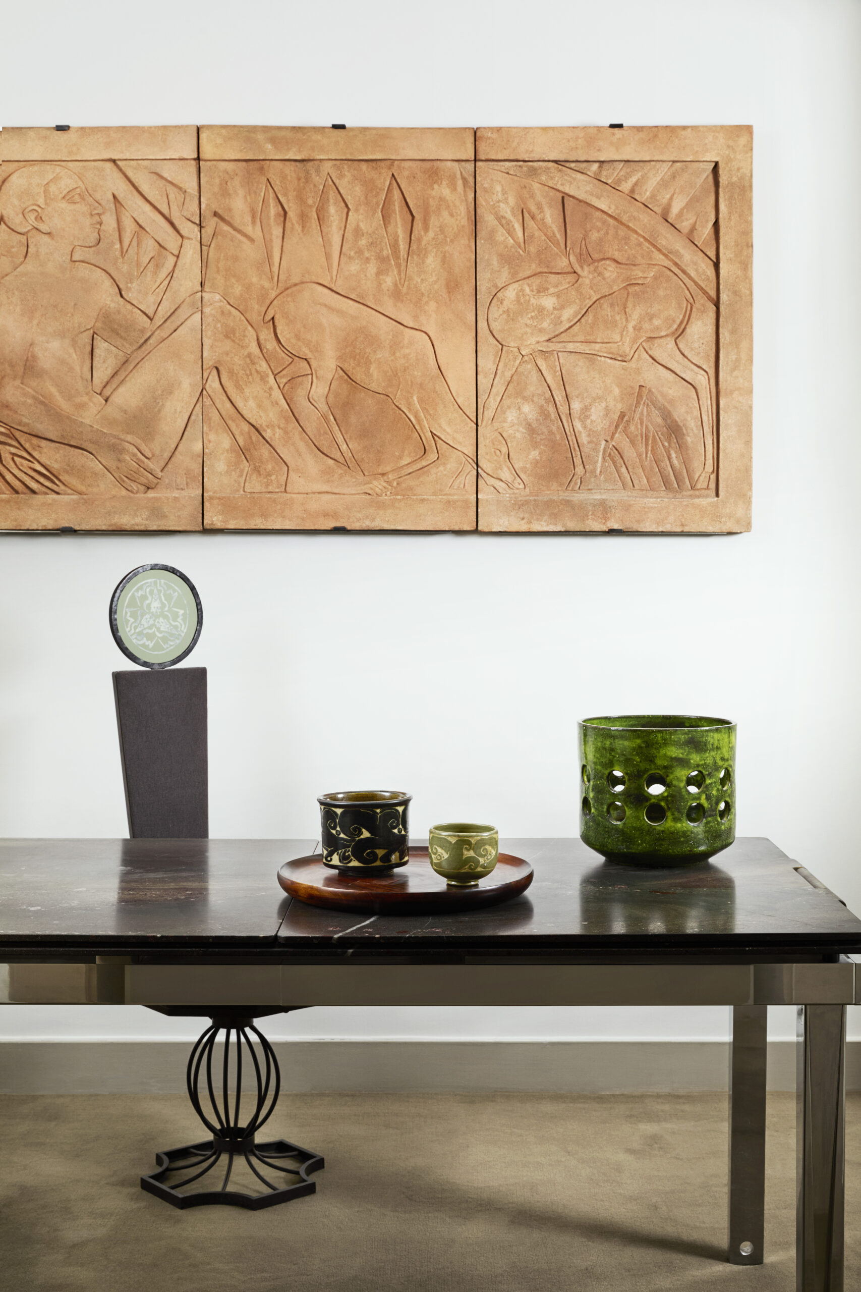 Shepherd and Antelopes ​Bas relief by Leon Indenbaum, 1913, chamotte clay, above " A livre ouvert ", a dining folding table with aluminium​ feet by Sylvain Dubuisson, 2018. « Ball » chairs by Serge Roche, c.1936. with iron foot by Gilbert Poillerat and painted glass medallion by Camille Roche​. Ceramics by Mado Jolain et Emile Lenoble.