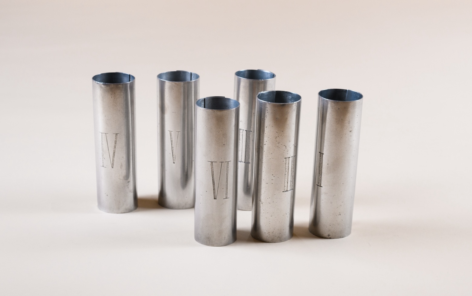 Set of six tubular napkin rings by Pierre Legrain, hammered and rolled zinc plates, each engraved with a Roman numeral from I to VI, c. 1920.